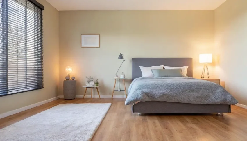 A cozy modern bedroom with cream-colored walls, pastel accents, elegant furnishings, and natural lighting.